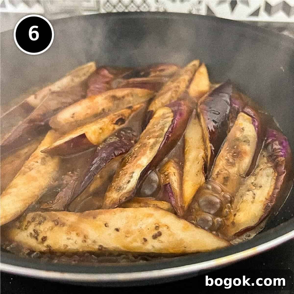 Chinese eggplant simmering to thicken in a wok for Chinese eggplant