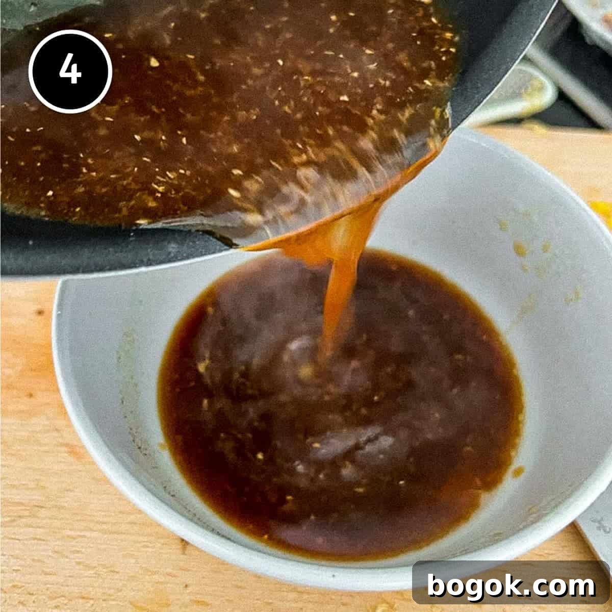 pouring the thick cooking sauce for Chinese eggplant into from a wok into a small bowl
