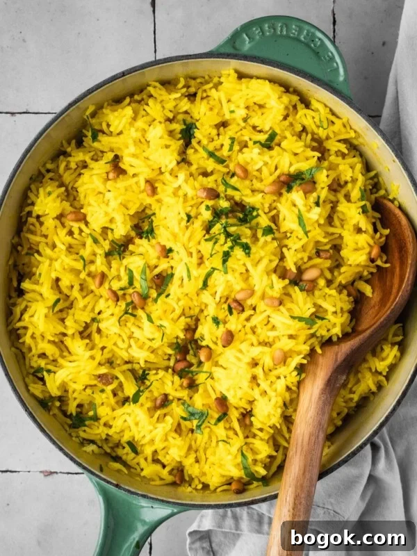 Mediterranean yellow rice in a pot garnished with pine nuts and fresh parsley.