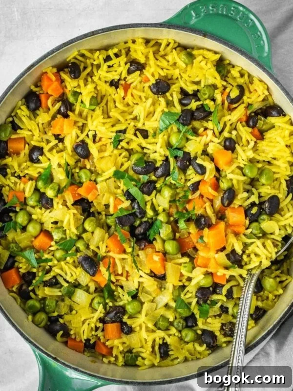 Middle Eastern Vegetable Rice Pilaf with peas, carrots and black beans, garnished with fresh parsley in a pot.