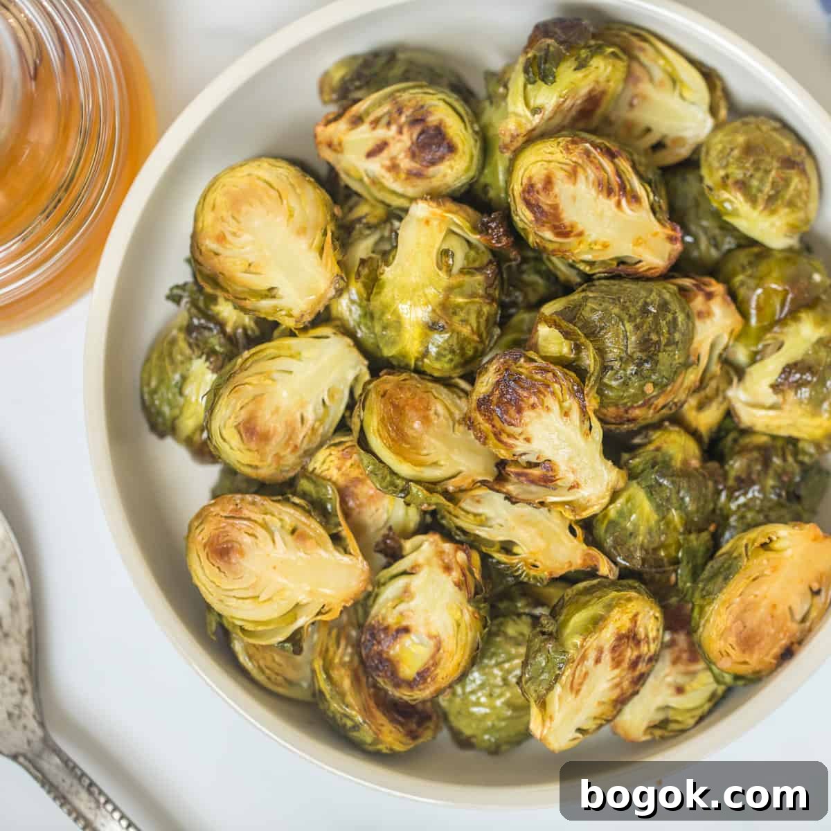 Thanksgiving Dinner Ideas Roasted Brussels sprouts in serving bowl with honey jar in background.