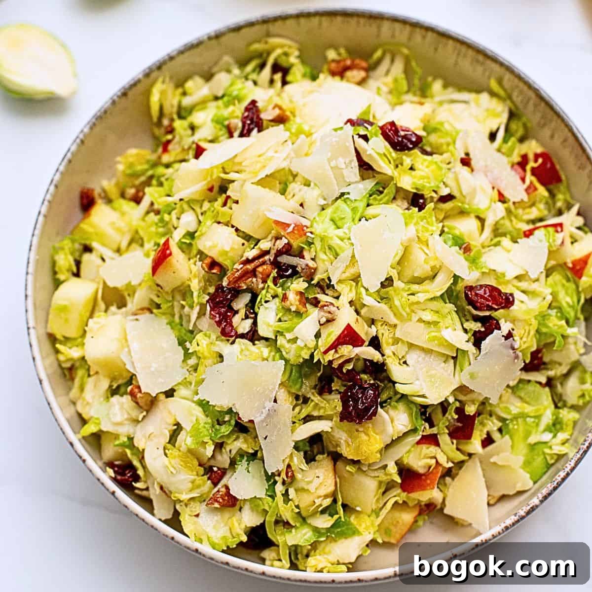 Ideas for Easy Thanksgiving Dinner Salad dished out made with shaved Brussels Sprouts tossed with honey lemon dressing, diced apples, dried cranberries, shaved parmesan, and chopped toasted pecans.
