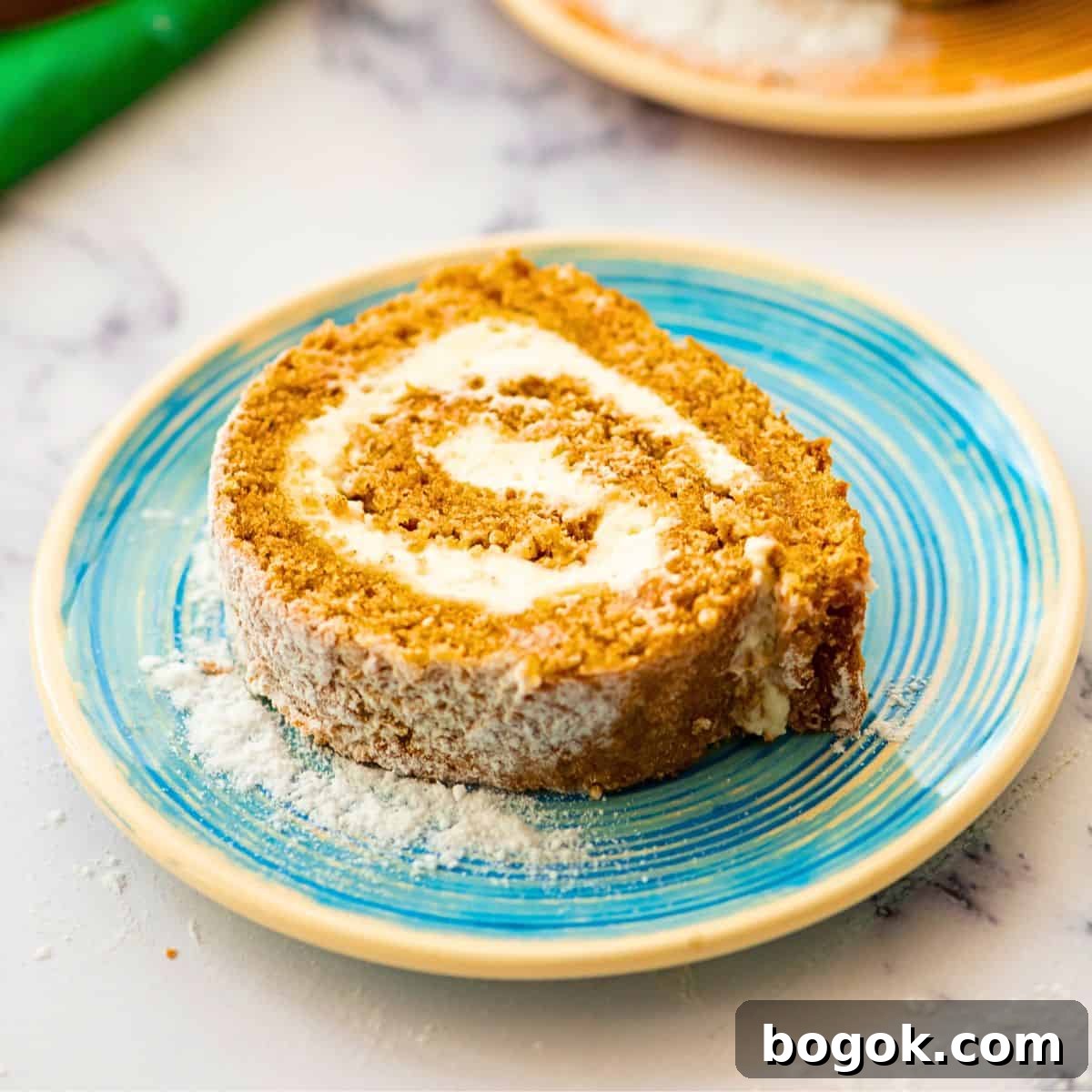 Simple Recipes for Thanksgiving Slice of homemade pumpkin roll showing light pumpkin cake with cream cheese swirl.
