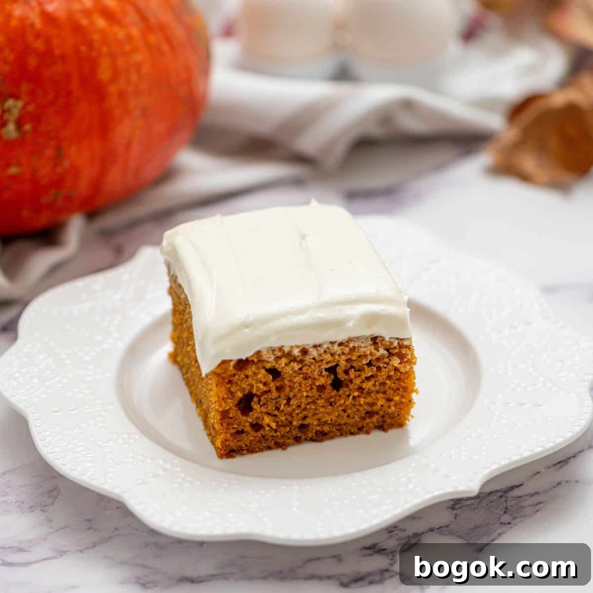 Recipes for Easy Thanksgiving Slice of pumpkin cake with cream cheese frosing on white plate.