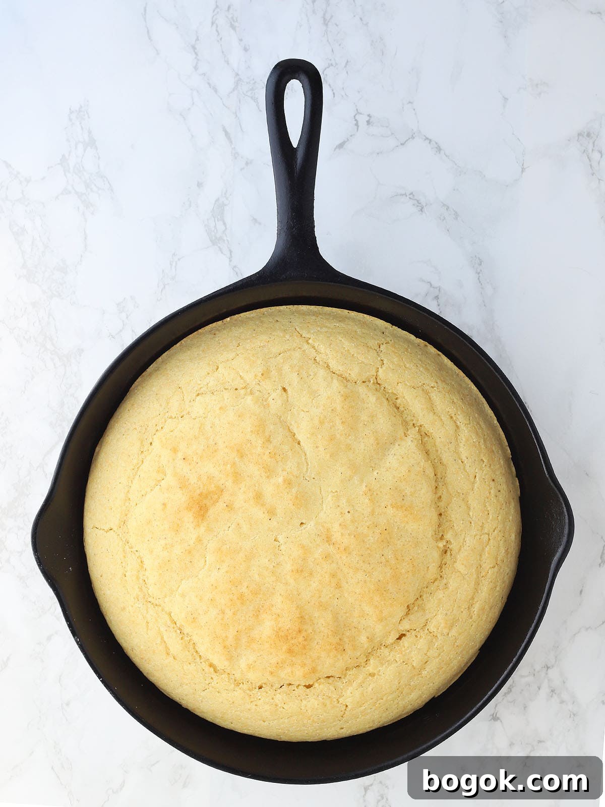 Classic Southern Skillet Cornbread Recipe for Crispy Golden Crust 13 Baked cornbread in a cast iron skillet on a white background.