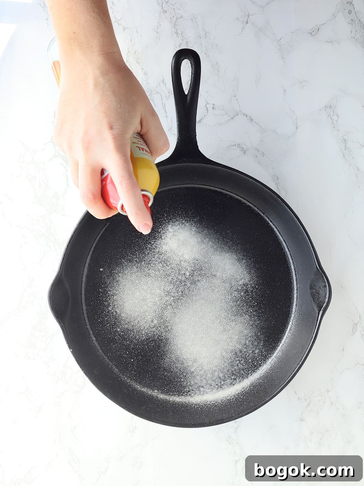 Classic Southern Skillet Cornbread Recipe for Crispy Golden Crust 4 Hand spraying a cast iron skillet with cooking spray.