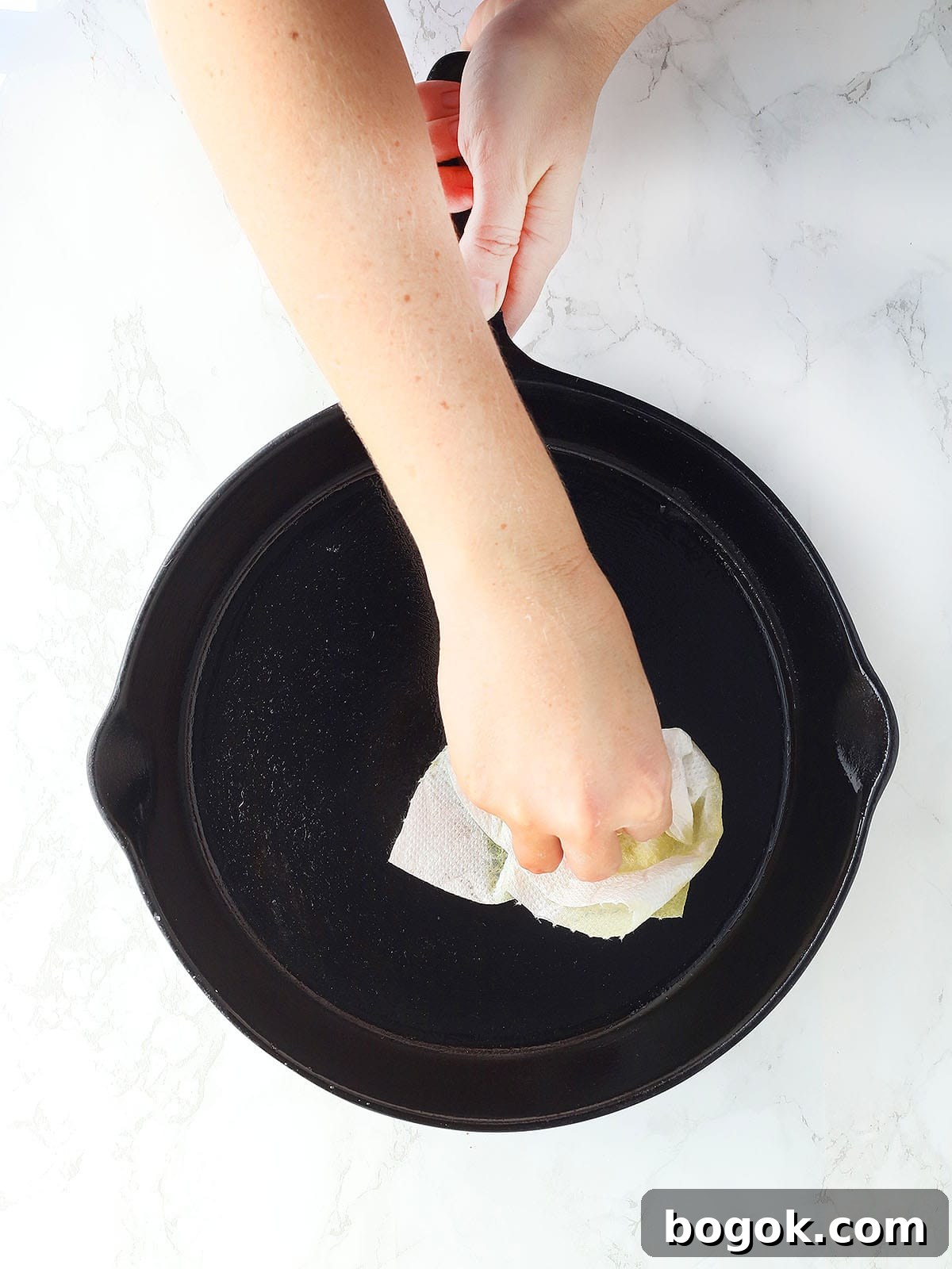 Classic Southern Skillet Cornbread Recipe for Crispy Golden Crust 5 Hand wiping excess oil out of a cast iron skillet.