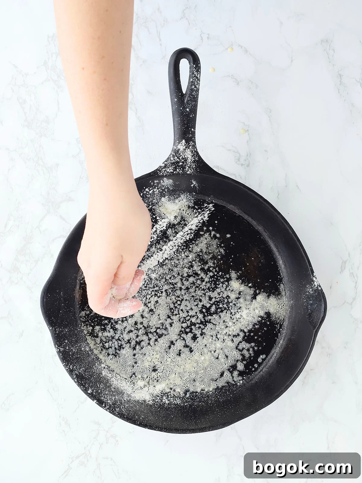 Classic Southern Skillet Cornbread Recipe for Crispy Golden Crust 6 Hand sprinkling flour onto a greased cast iron skillet.