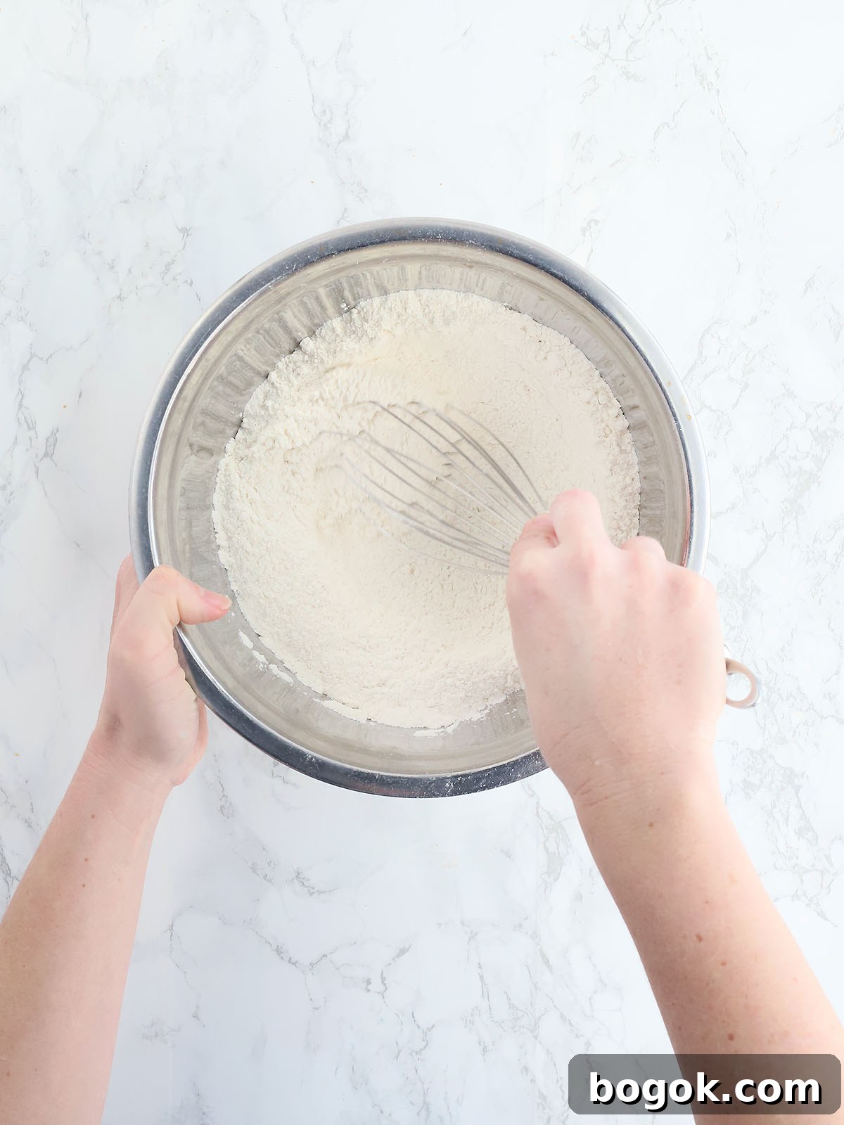 Classic Southern Skillet Cornbread Recipe for Crispy Golden Crust 7 Hands whisking cornmeal, baking powder and flour together.