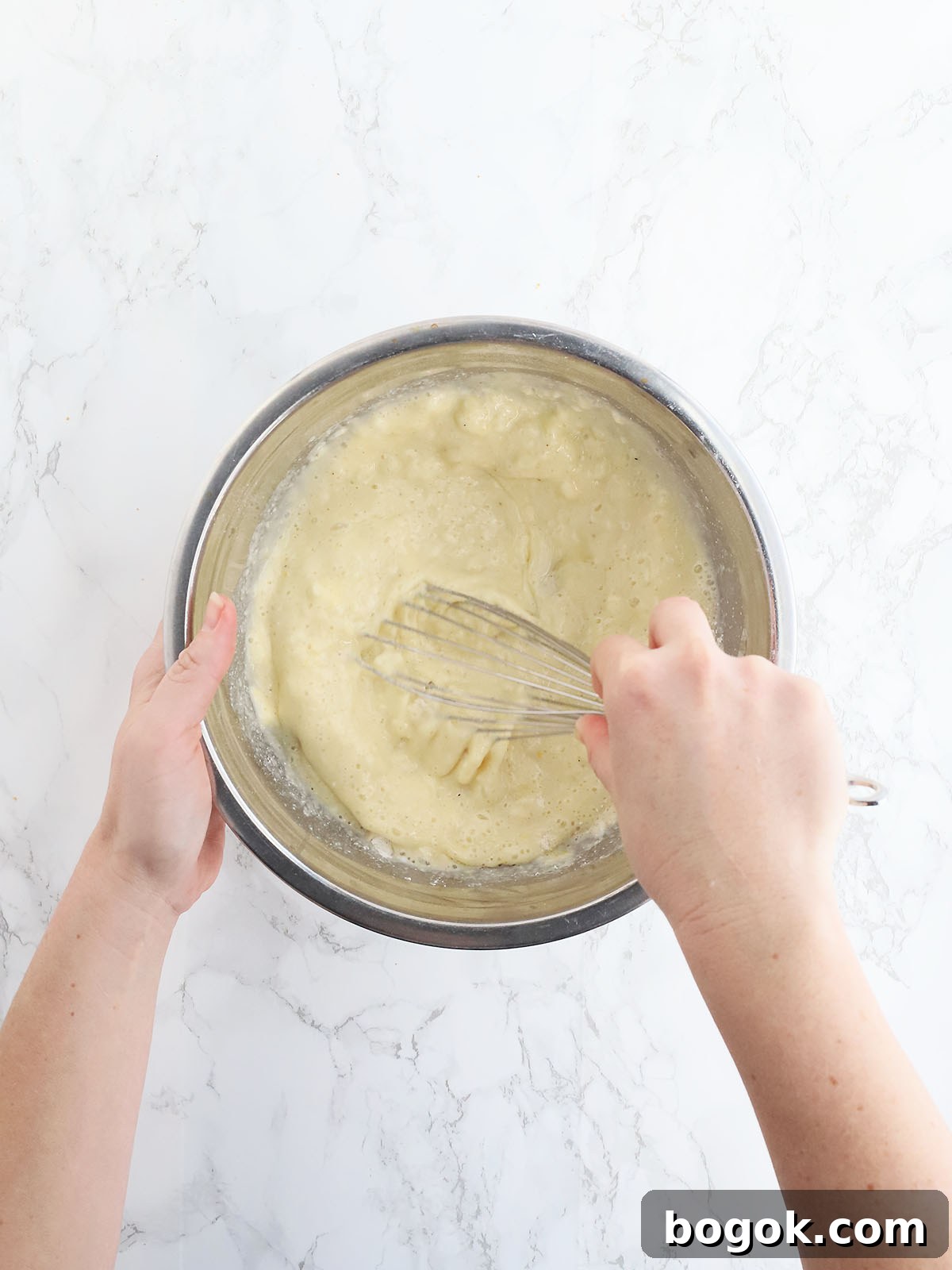 Classic Southern Skillet Cornbread Recipe for Crispy Golden Crust 10 Hand whisking together cornbread batter in a metal mixing bowl.