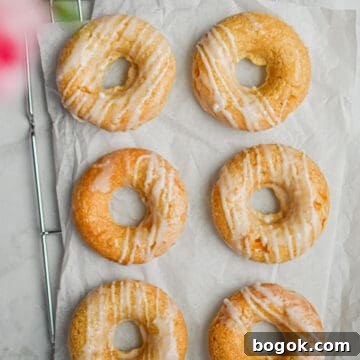 Baked Dairy-Free Peach Donuts Recipe 11 Six peach kefir doughnuts are laid out on a parchment paper on top of a wire rack.