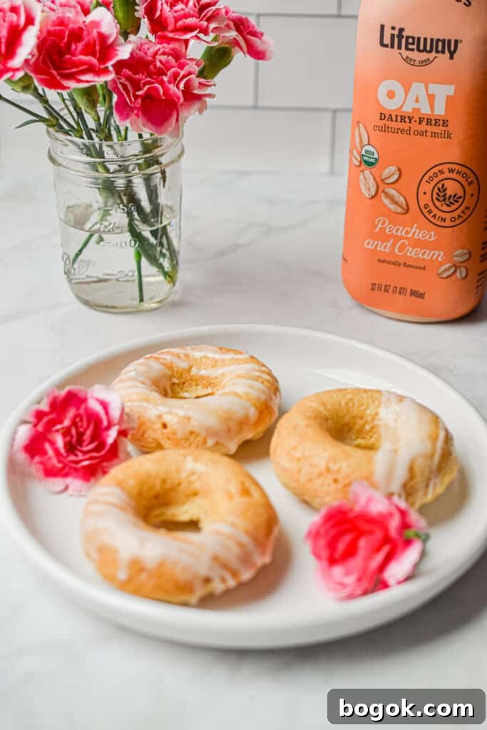Baked Dairy-Free Peach Donuts Recipe 10 Three peach kefir donuts are on a circle plate with a bottle of kefir in the background.