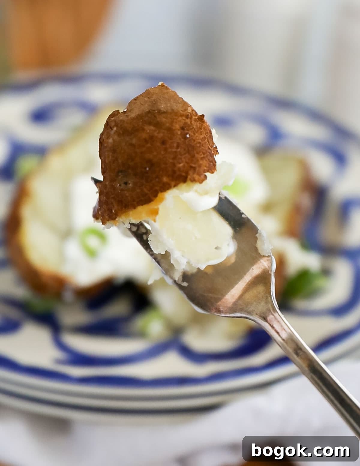 A fork holding up a bite of cooked russet potato.