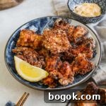 Crispy karaage chicken on a blue Japanese porcelain plate with a lemon wedge, chopsticks, and a small bowl of Kewpie mayo for dipping.