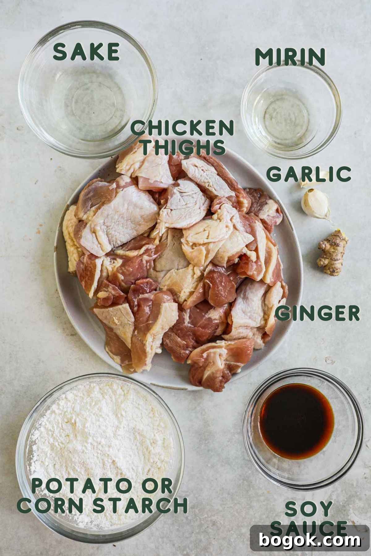 Ingredients to make Japanese fried karaage chicken, chicken thighs, sake, mirin, garlic, ginger, potato or corn starch, soy sauce.