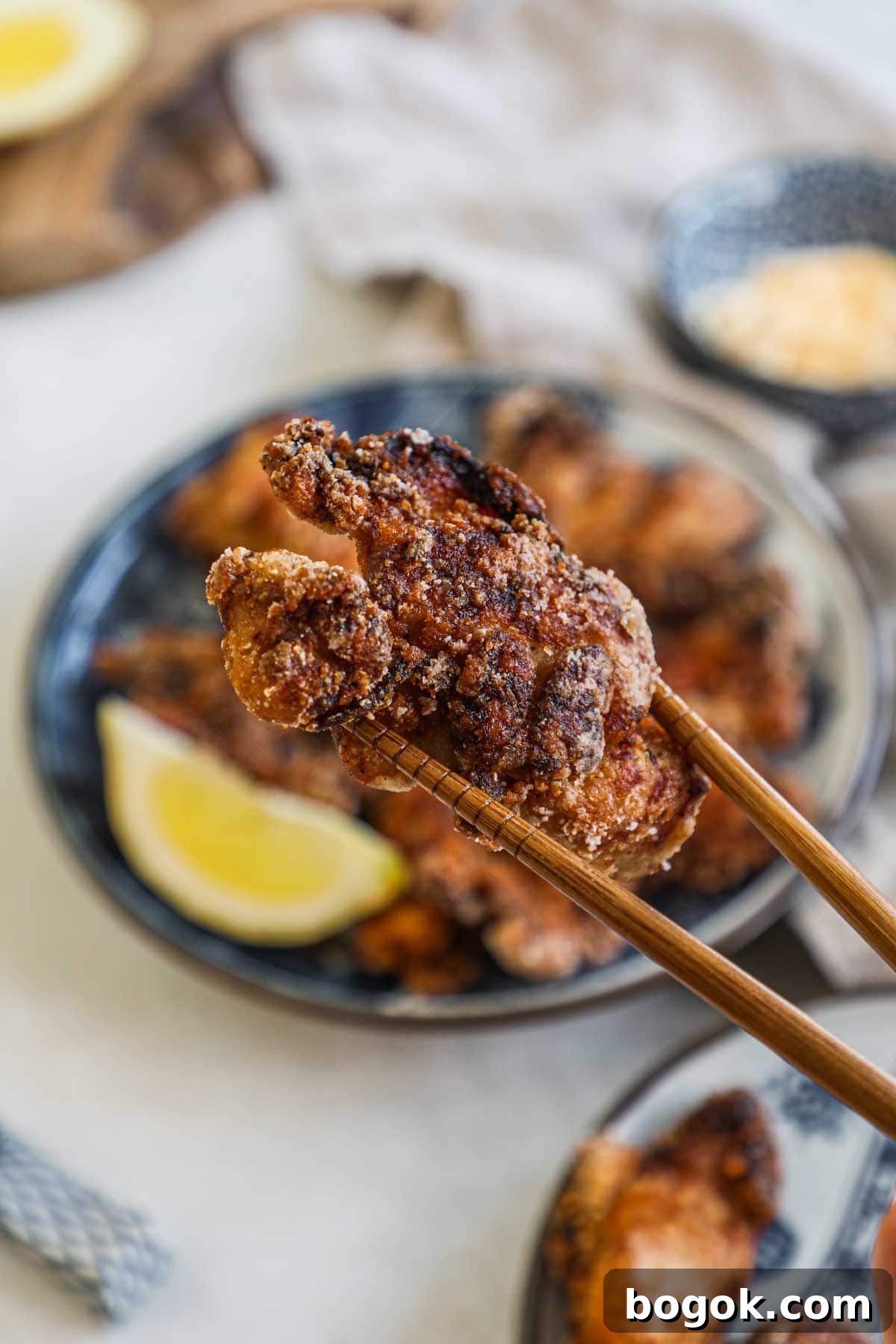 Chopsticks holding a piece of golden Japanese fried chicken.