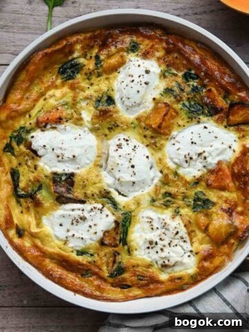 Overhead of a cooked frittata in a white skillet on a wood surface.