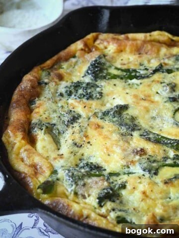 Close-up of broccolini frittata in a skillet with parmesan cheese in the background.