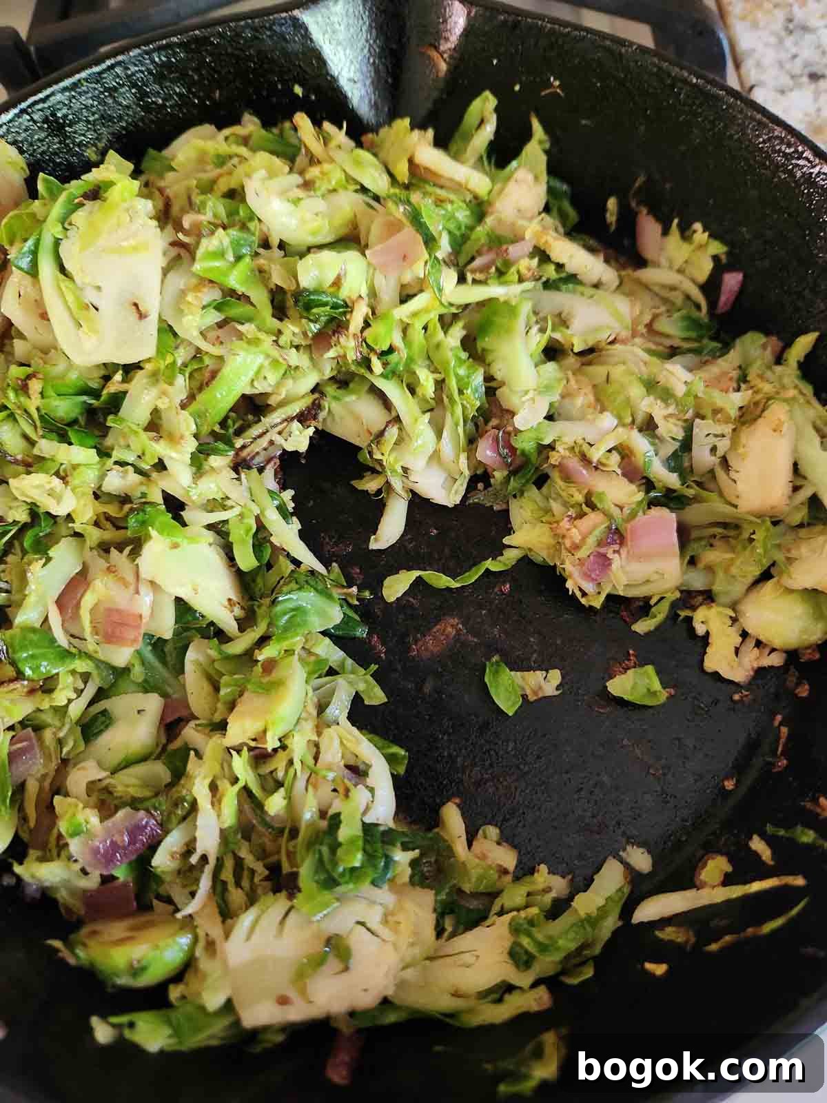 Crispy Brussels Sprout Hash with Bacon and Caramelized Onions 7 Cooked Brussel sprouts in a black skillet.
