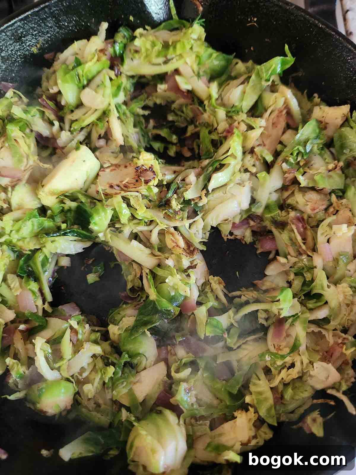 Crispy Brussels Sprout Hash with Bacon and Caramelized Onions 8 Brussel sprout hash in a skillet with 3 holes in it for eggs.