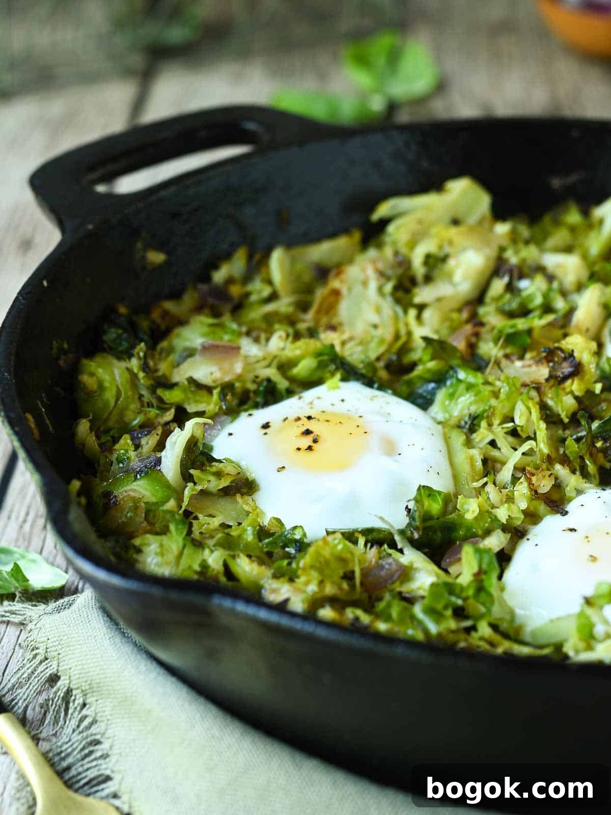 Crispy Brussels Sprout Hash with Bacon and Caramelized Onions 10 Brussel sprout hash in a black skillet with eggs.