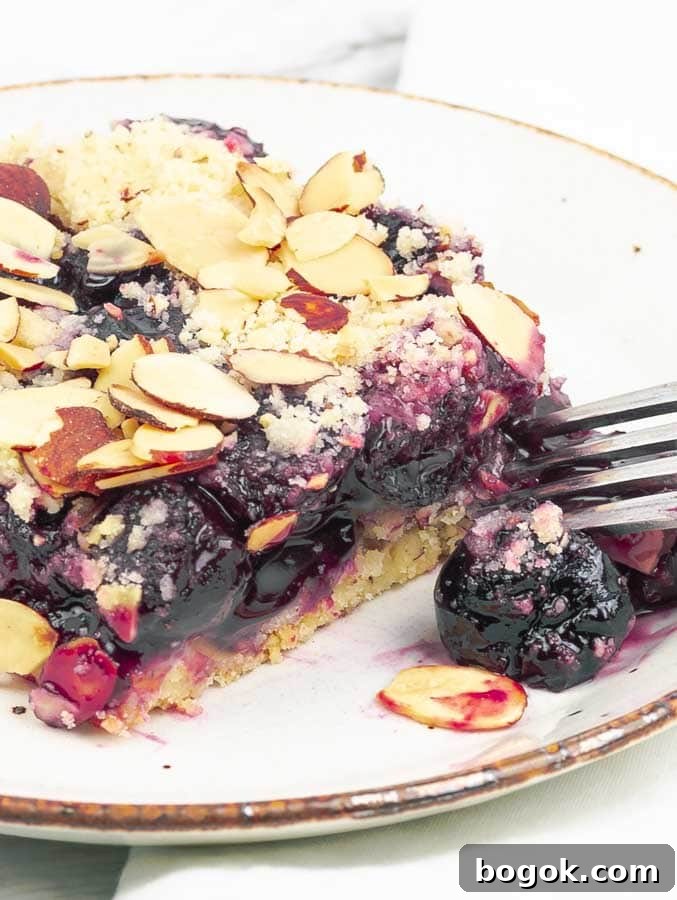 close up of a cherry almond pie bar on a white plate