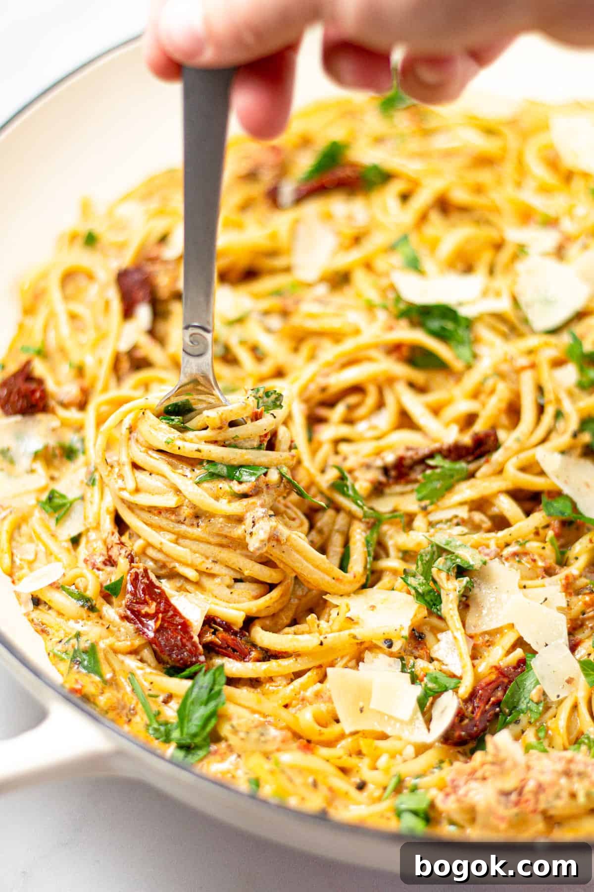 15-Minute Cream Tomato Pasta with Garlic and Basil 11 A fork twirling linguine in a large pan of sun-dried tomato pasta.