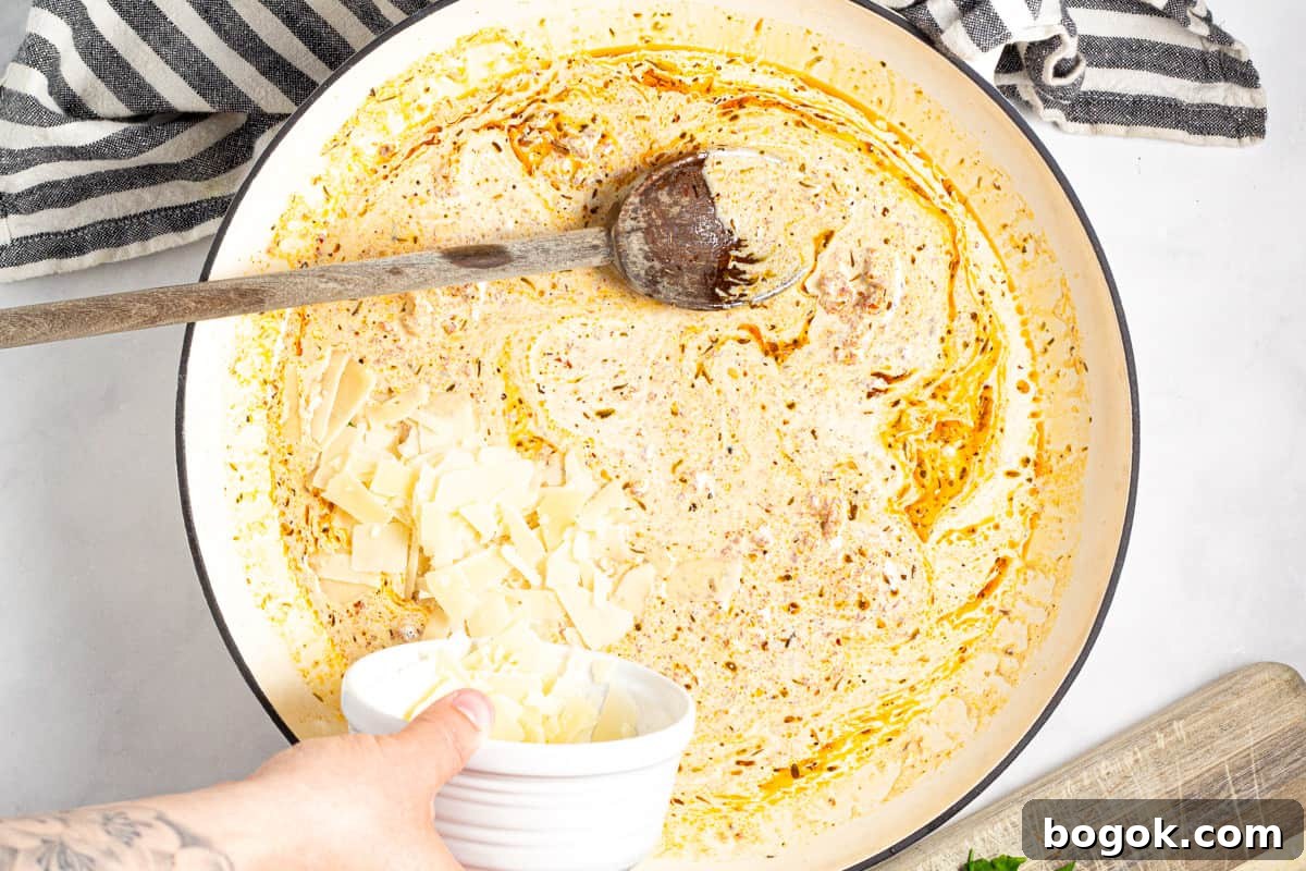 15-Minute Cream Tomato Pasta with Garlic and Basil 7 Parmesan cheese being added to a large pan of tomato cream sauce.