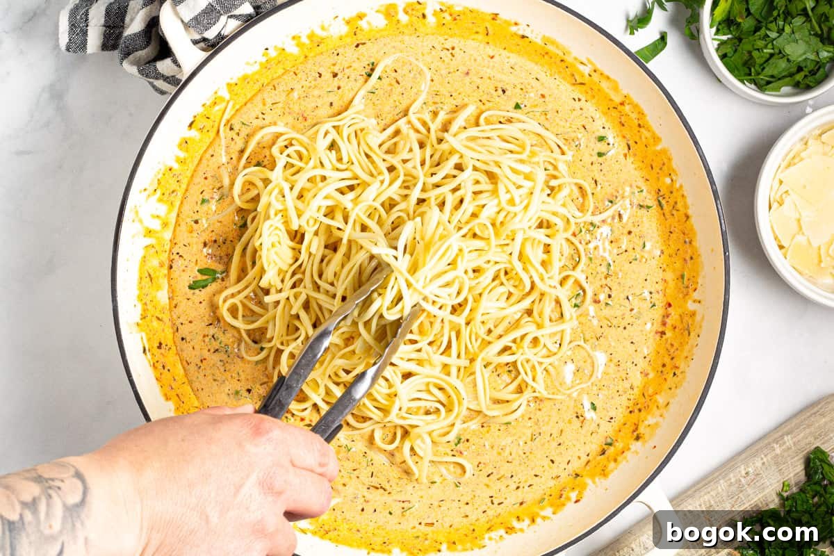 15-Minute Cream Tomato Pasta with Garlic and Basil 9 Noodles being tossed in a pan of creamy sun dried tomato sauce.