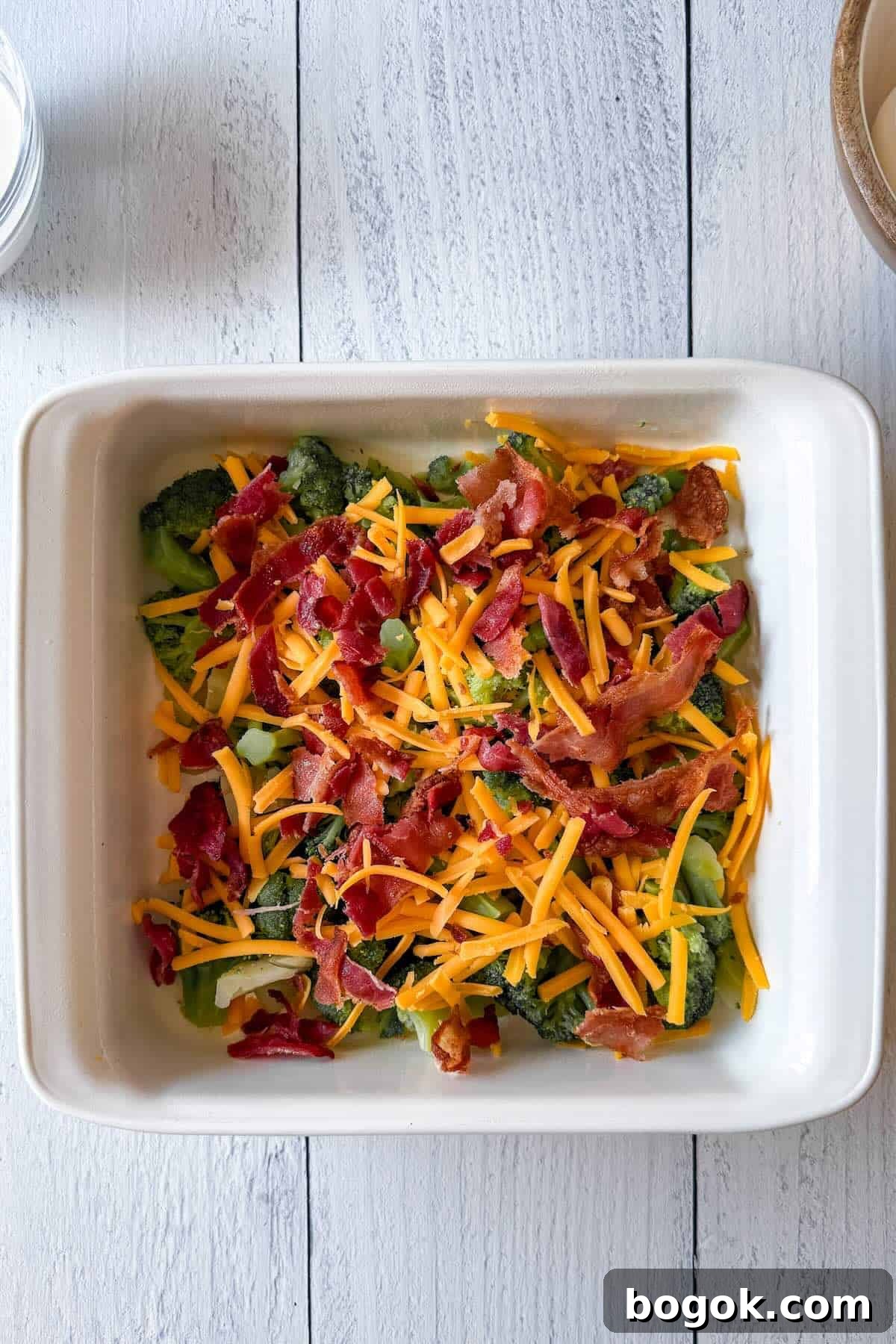 Low-Carb Bacon and Broccoli Breakfast Casserole 5 Broccoli, bacon, and shredded cheese layered in a baking dish for breakfast casserole.