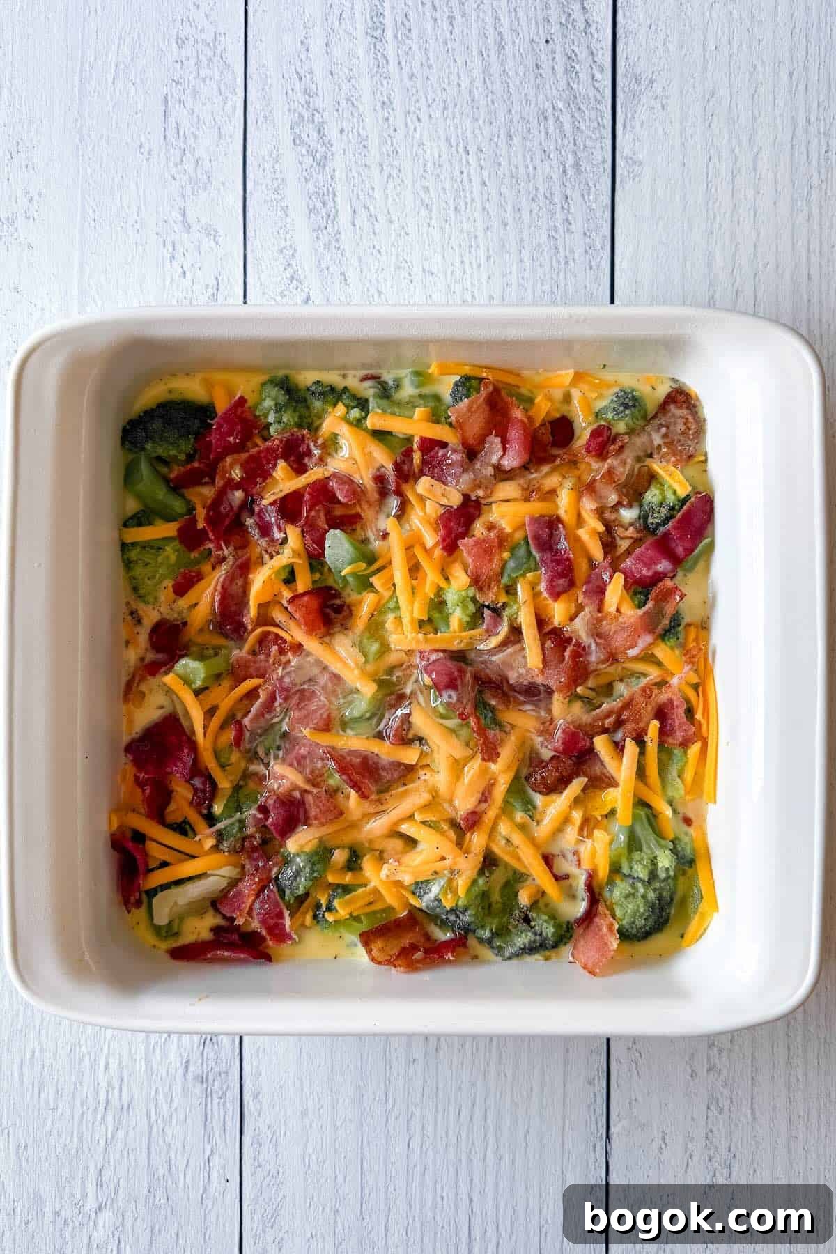 Low-Carb Bacon and Broccoli Breakfast Casserole 7 Unbaked bacon broccoli breakfast casserole in an 8x8 baking dish before going into the oven.