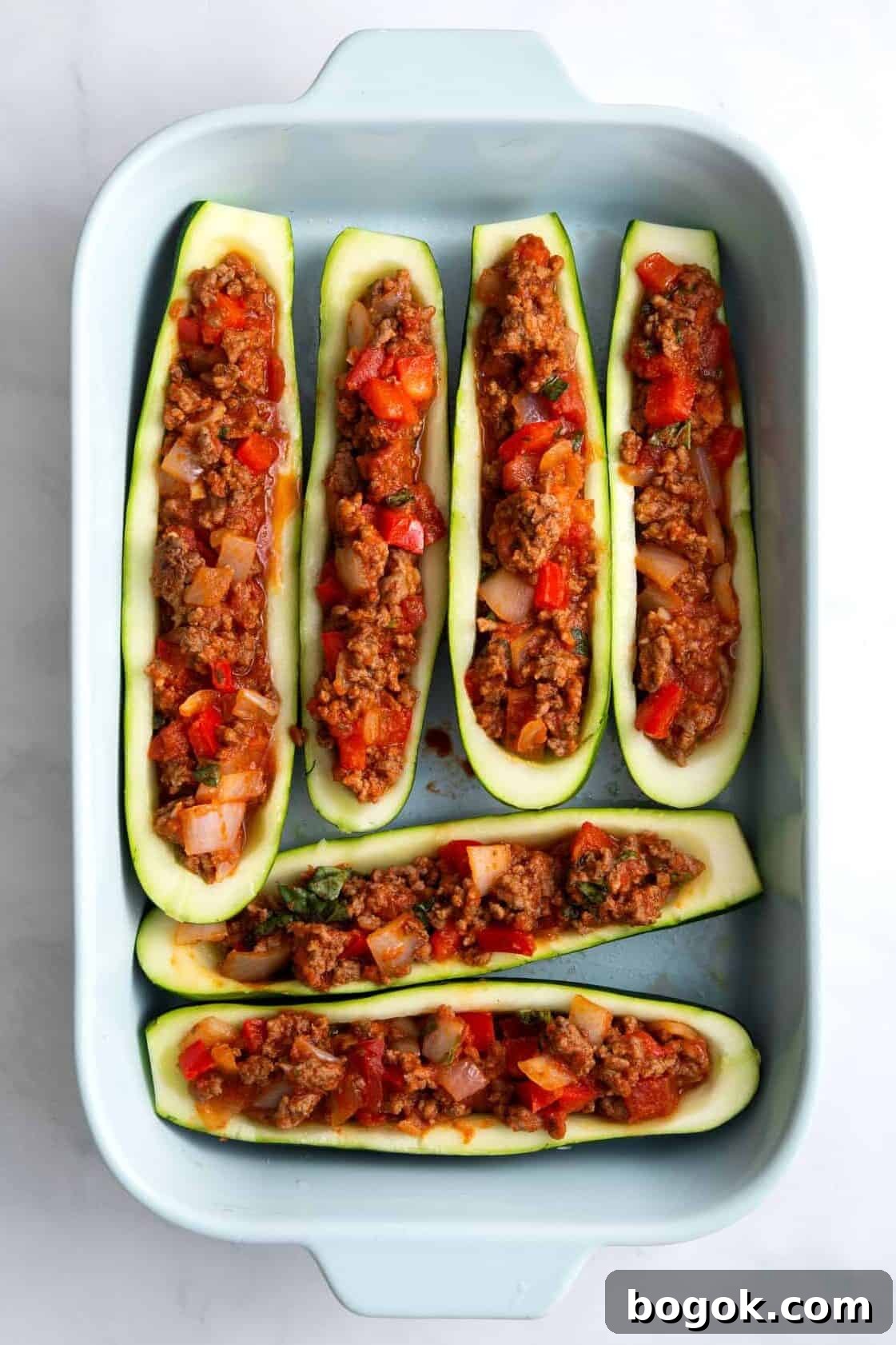 stuffed zucchini lined in a blue 9x13 casserole dish.