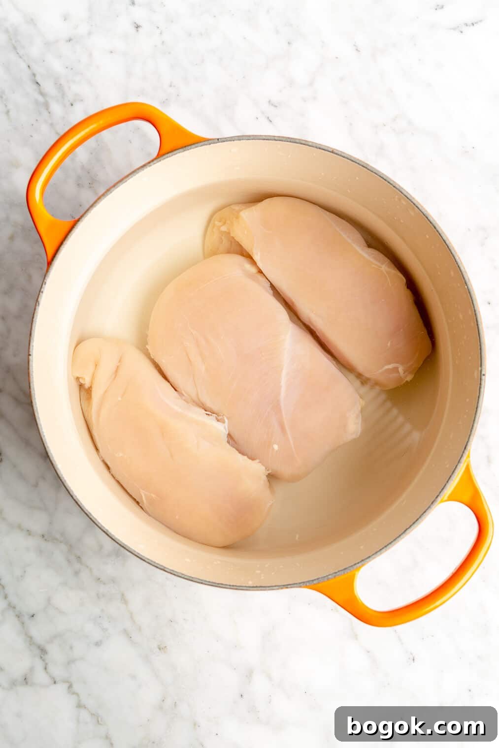 BBQ Chicken and Sweet Potato Casserole Recipe 5 A pot with 3 chicken breasts submerged in water.