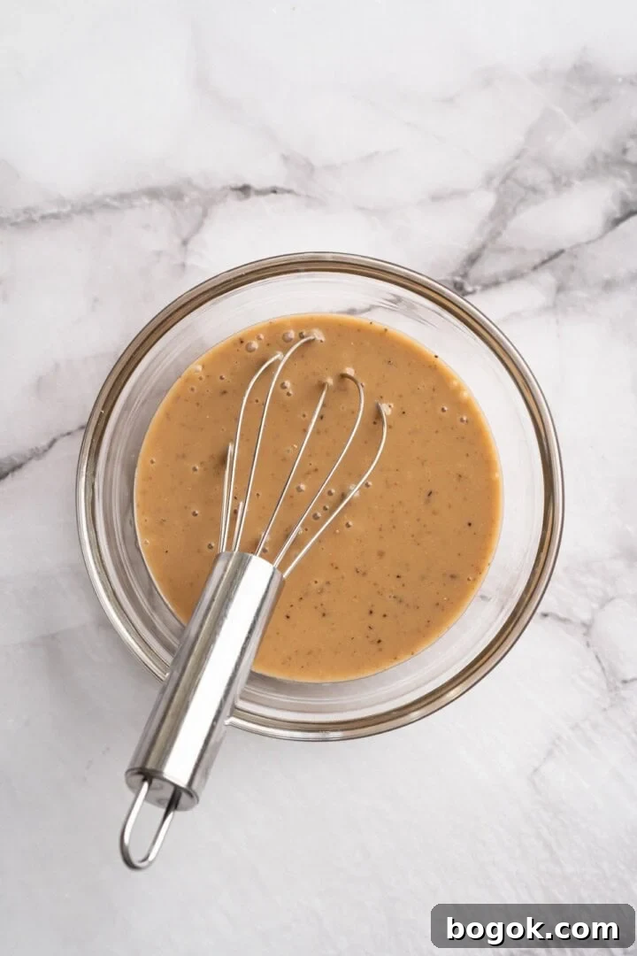 Overhead view of maple mustard vinaigrette in bowl with whisk