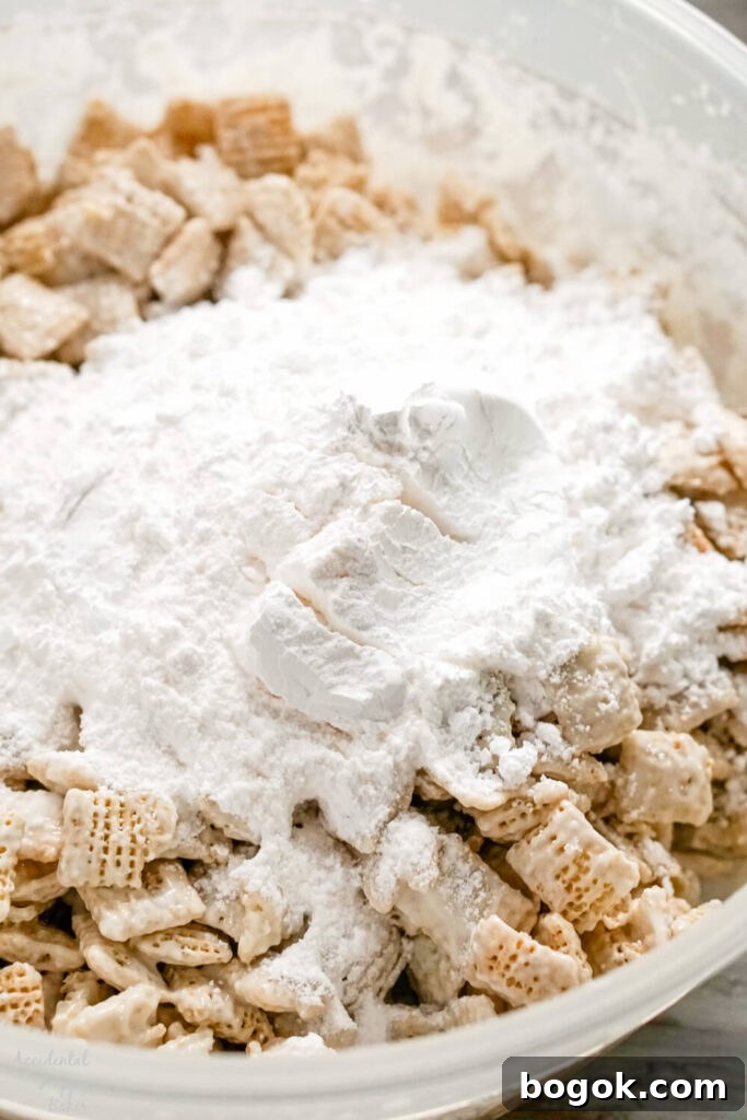 Almond bark covered cereal with powdered sugar and banana pudding mix in a bowl. 