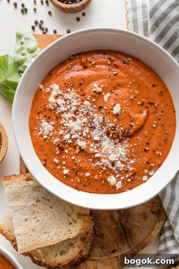 Bowl of velvety, rich tomato butternut bisque with fresh basil and thick-cut sourdough toast nearby.