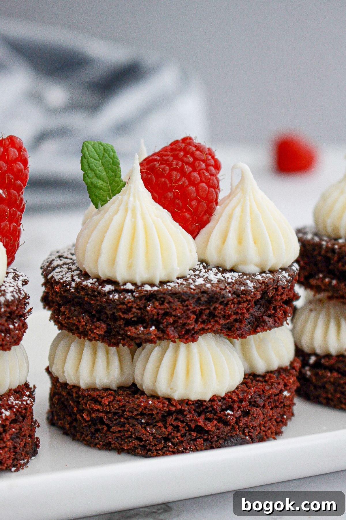 mini chocolate cake on a plate topped with a fresh raspberry.
