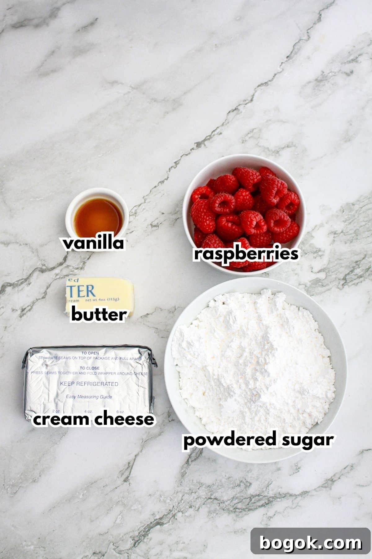 bowls of vanilla, butter, cream cheese, raspberries, powdered sugar on a counter to make the frosting.
