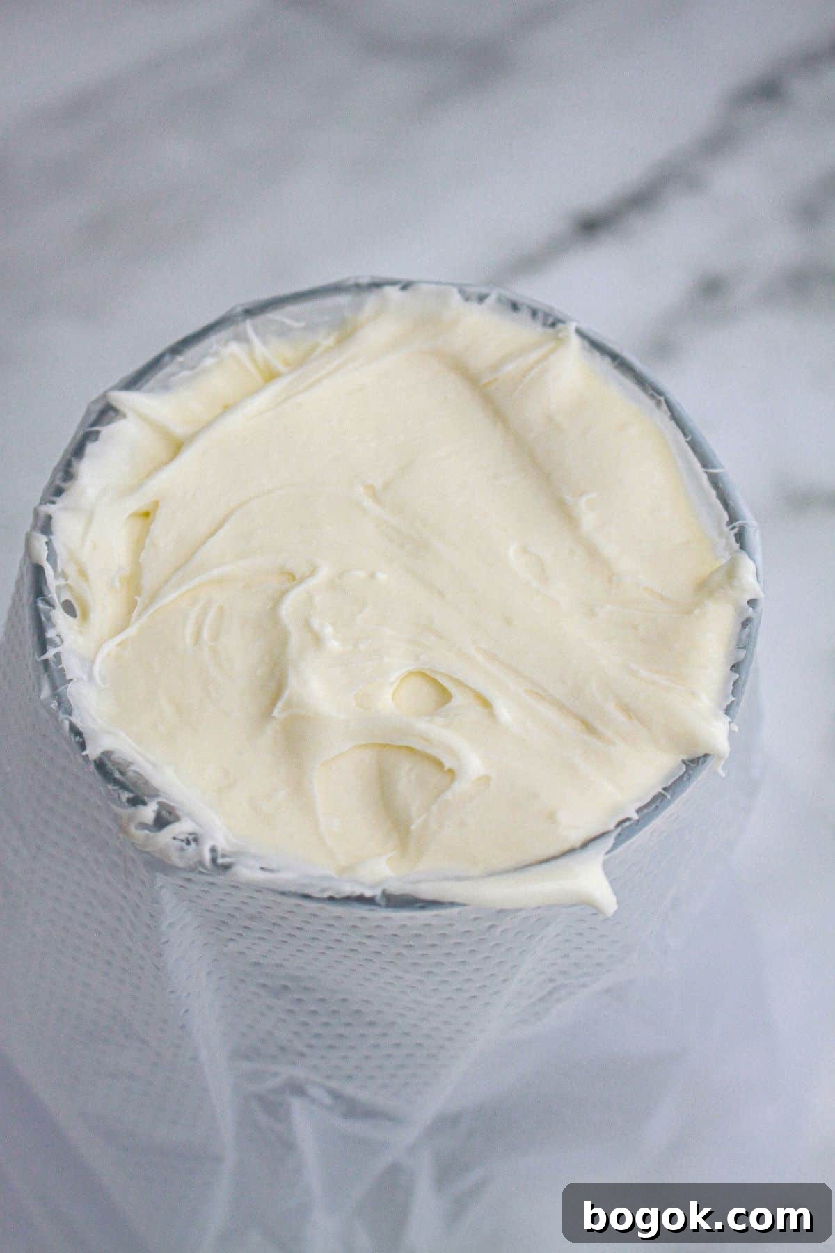 cream cheese frosting being added to a piping bag in a cup.