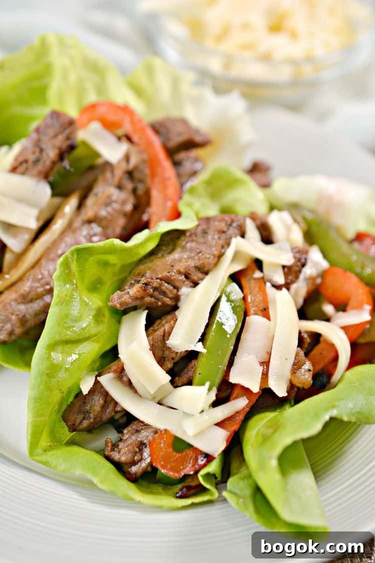 Philly Cheesesteak Keto Lettuce Wraps — Low-Carb Dinner Option 2 closeup of keto lettuce wraps on a white plate with shredded cheese on top