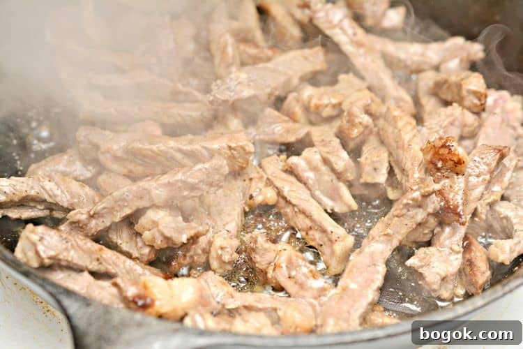 Philly Cheesesteak Keto Lettuce Wraps — Low-Carb Dinner Option 3 steak being cooked in a pan with steam coming off