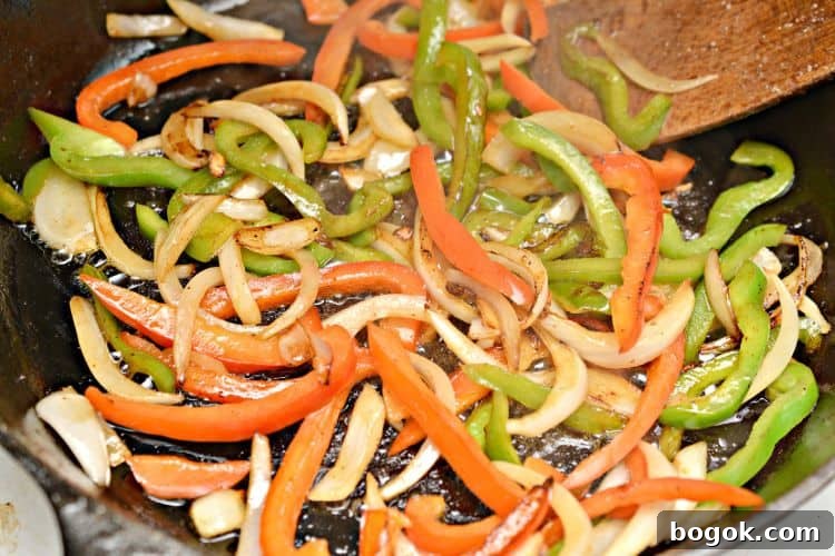 Philly Cheesesteak Keto Lettuce Wraps — Low-Carb Dinner Option 4 onion and peppers in a pan being cooked for keto lettuce wraps