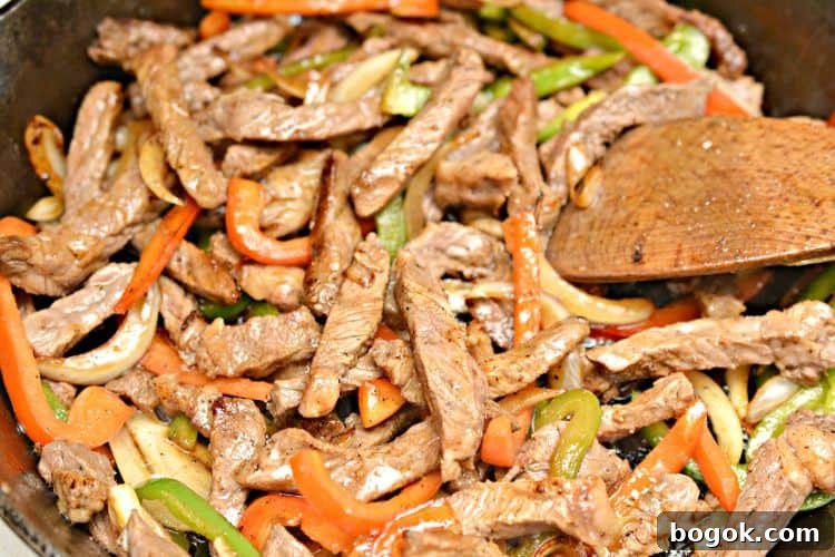 Philly Cheesesteak Keto Lettuce Wraps — Low-Carb Dinner Option 5 steak, peppers, and onions cooked in a pan next to a wooden spatula