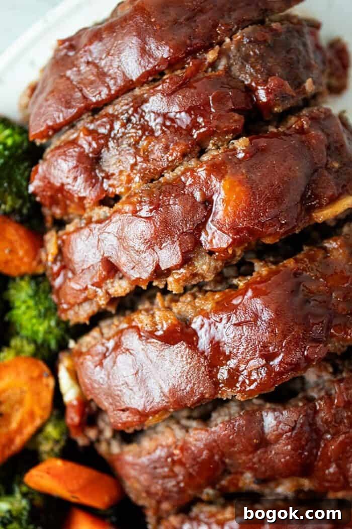 Philly Cheesesteak Keto Lettuce Wraps — Low-Carb Dinner Option 9 overhead view of sliced keto meatloaf with ketchup glaze on a white serving dish and carrots and broccoli on the side
