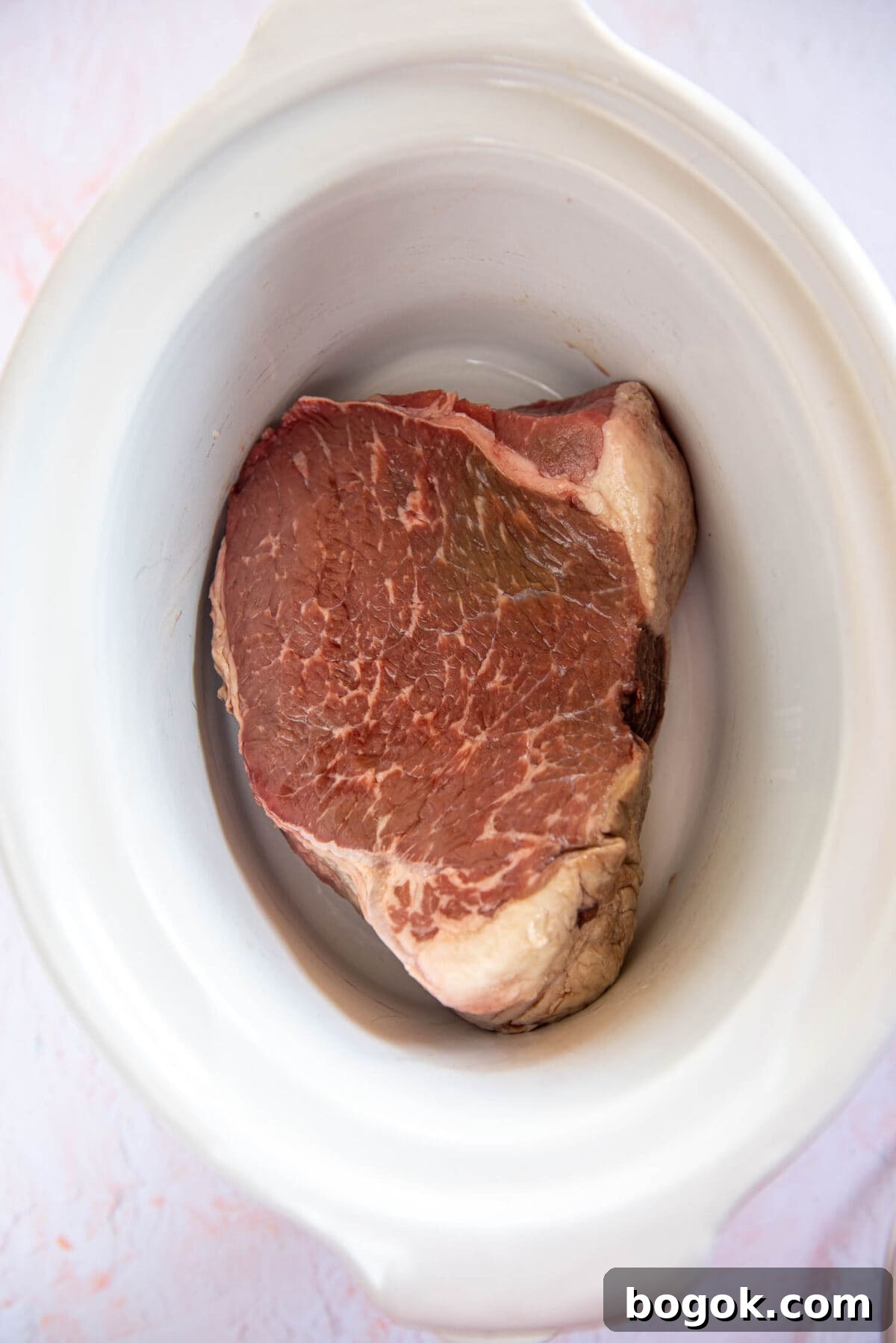 Mississippi Pot Roast Recipe for Tender Slow-Cooker Comfort 4 uncooked roast meat inside if white slow cooker bowl