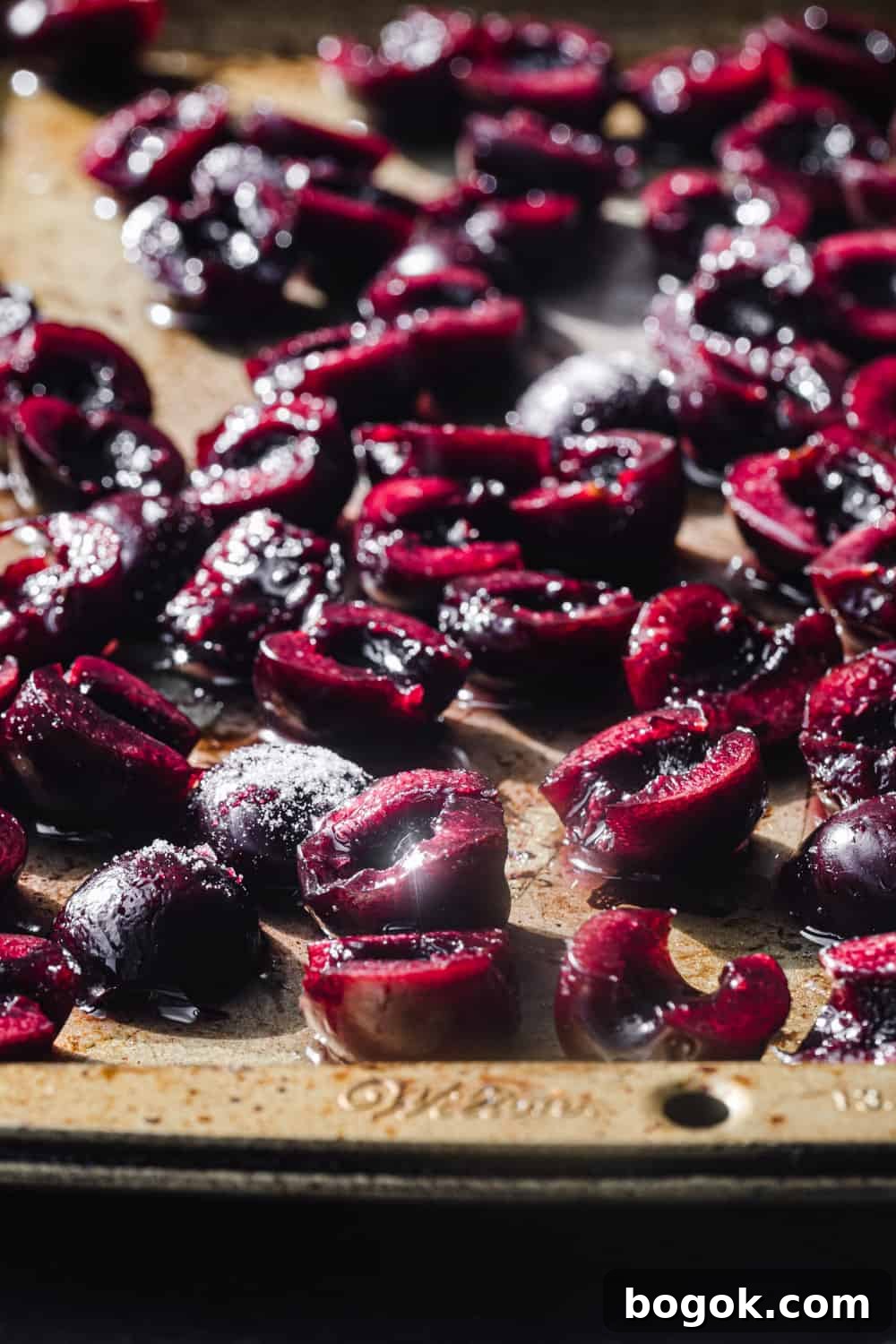 Roasted Cherries in 15 Minutes: Sweet, Syrupy Recipe 7 Side angle shot of raw cherries with sugar on a gold baking sheet, all ready to go in the oven and be roasted.