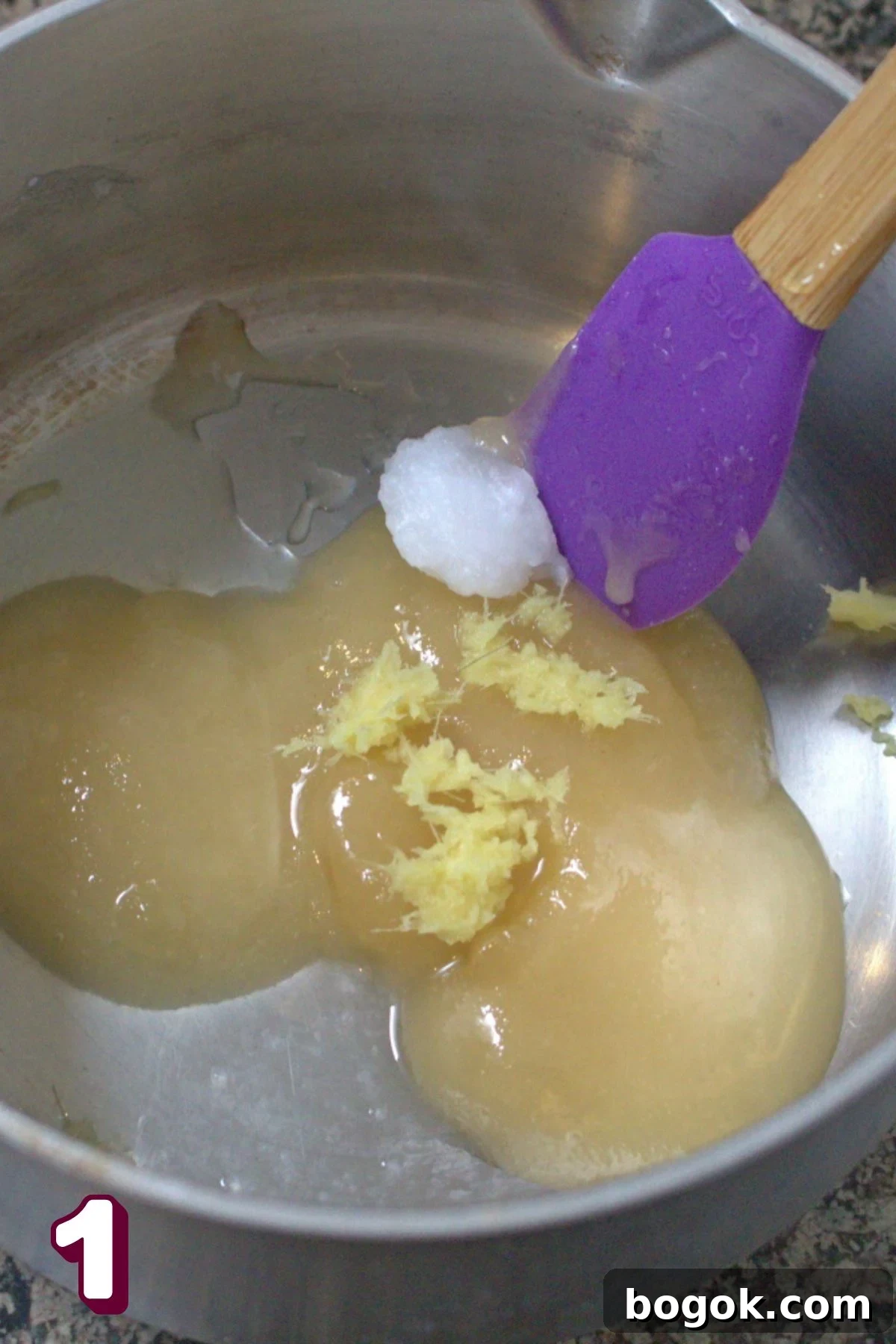 Coconut oil, honey, lemon, and ginger in a small pot with a purple spatula.