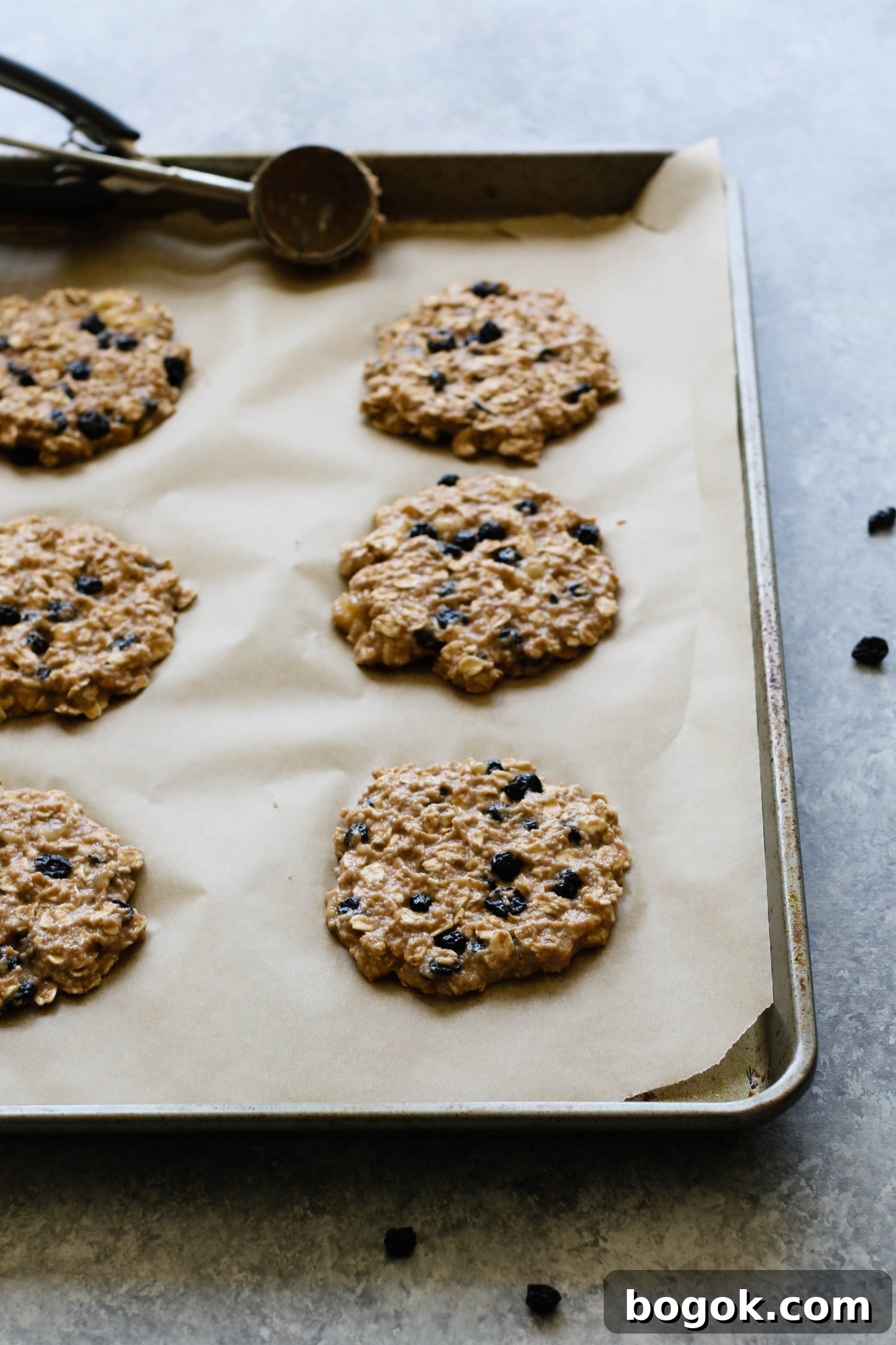 Blueberry Banana Breakfast Cookies raw on parchment lined baking sheet with cookie dough scoop