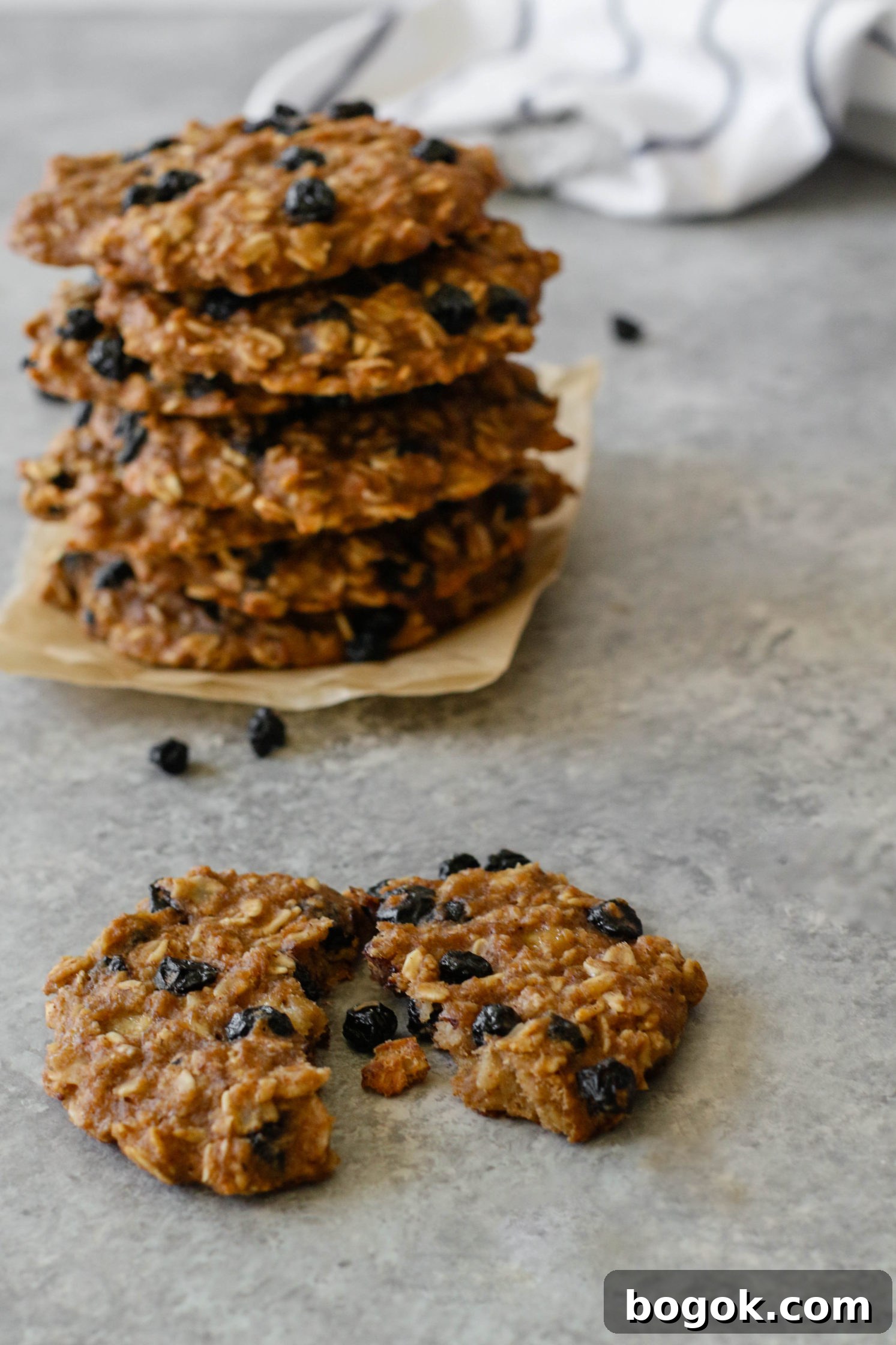 Blueberry Banana Breakfast Cookies stacked on parchment paper with one cookie broken open in front