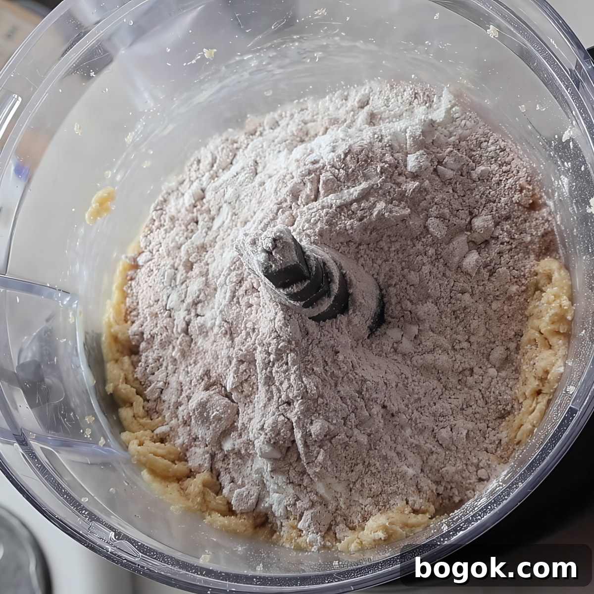 light brown flour on top of dough in food processor bowl.